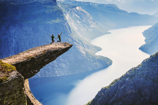 A couple at the edge of a cliff, surrounded by tall mountains and a flowing river, symbolizing the concept of consequentialism, where actions are evaluated based on their consequences.
